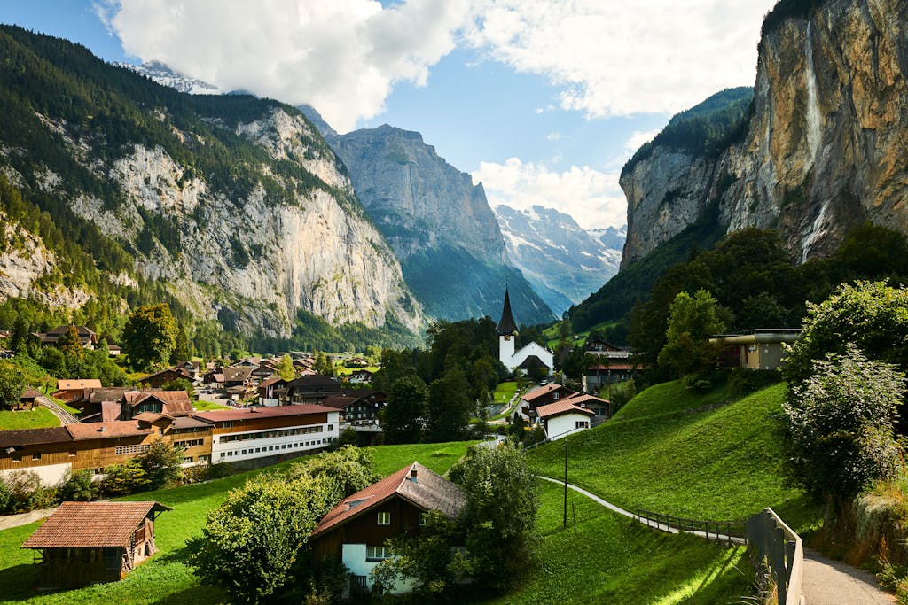 Scenic landscape of Lauterbrunnen Valley with traditional Swiss chalets and dramatic mountain cliffs in summer.