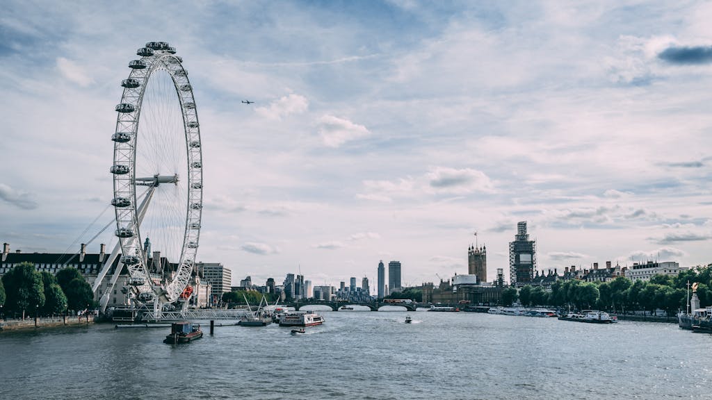 Scenic view of the London Eye on the River Thames with clear blue skies and city skyline.