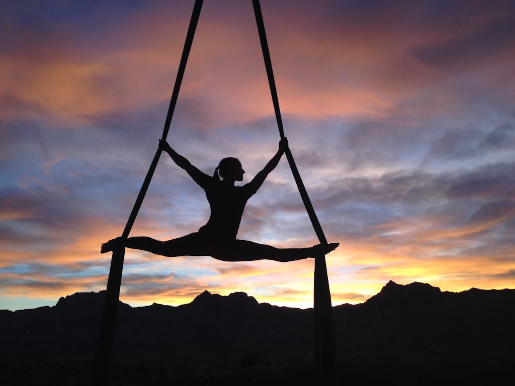 Silhouette of a woman practicing aerial yoga against a vibrant sunset sky in Las Vegas.