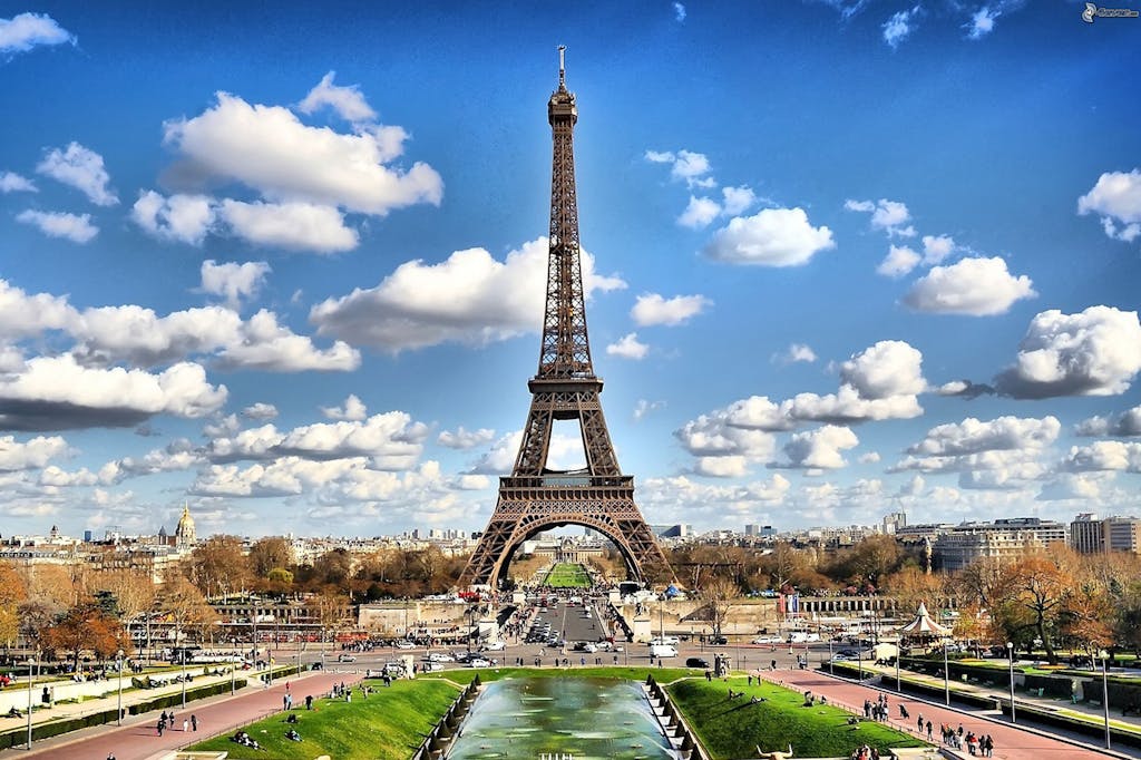 Stunning view of the Eiffel Tower with a backdrop of fluffy clouds and blue sky in Paris.