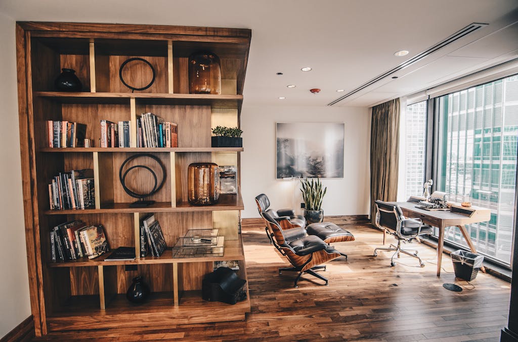 Stylish office space featuring a wooden bookshelf and a minimalist desk setup, ideal for work.