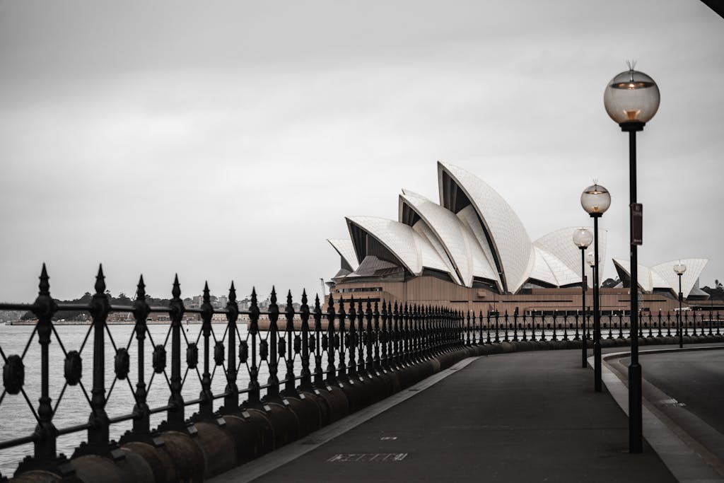 The iconic Sydney Opera House against a gloomy sky, viewed from the waterfront.