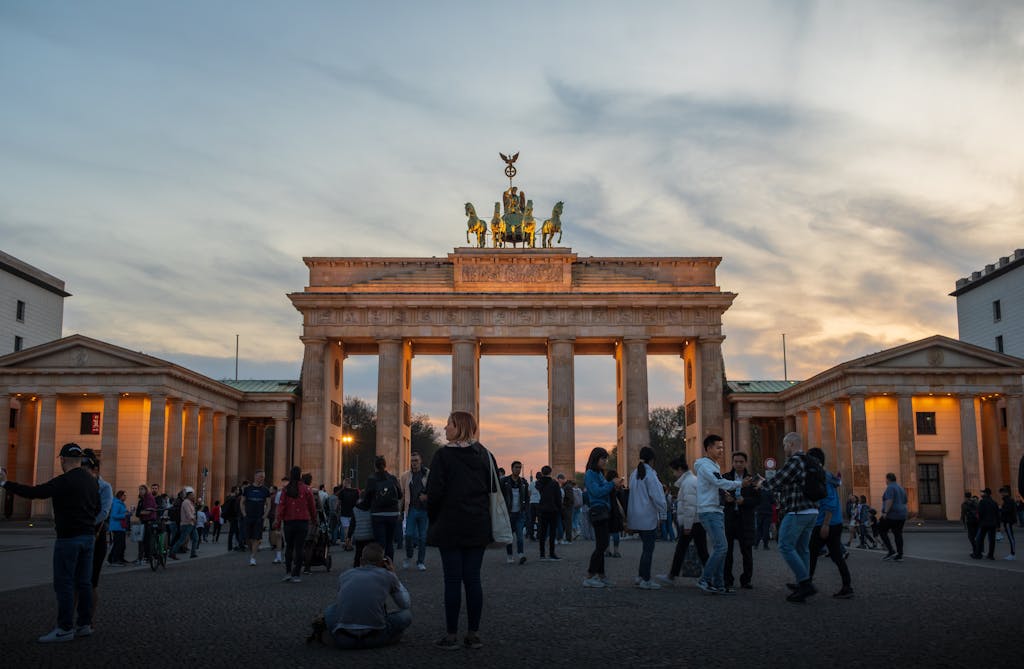 Tourists gather at Berlin's Brandenburg Gate during sunset, capturing its historic beauty.