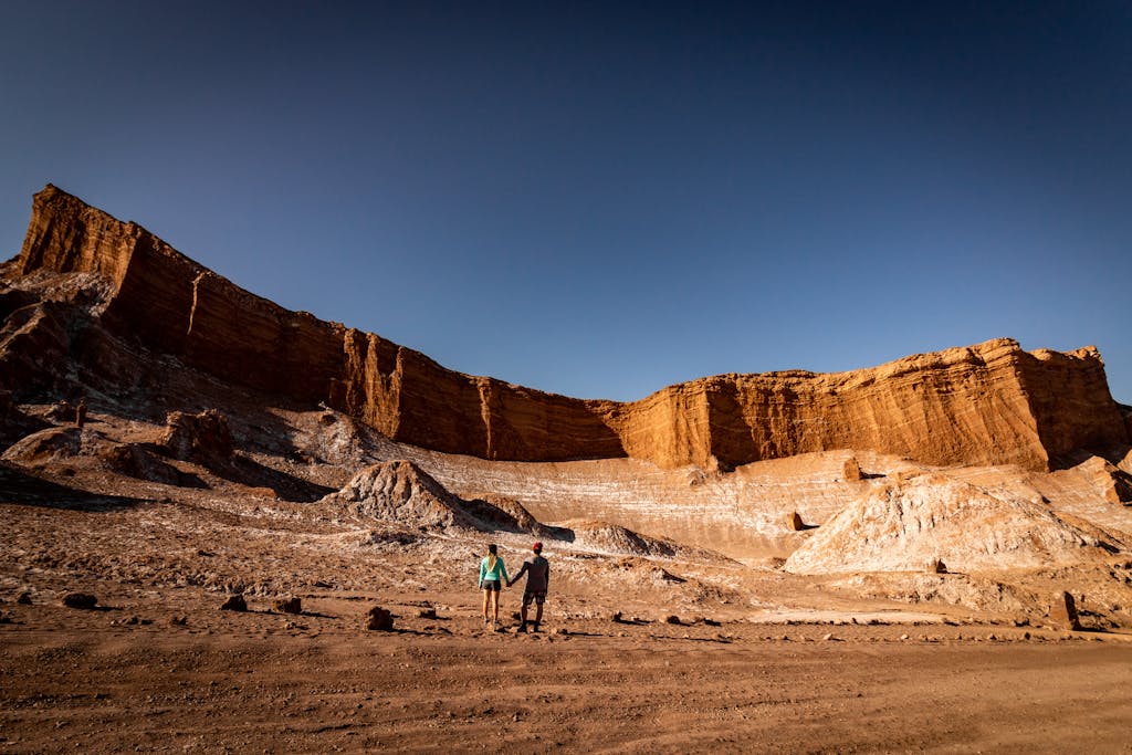 Two people exploring a scenic canyon in the arid Atacama Desert, Chile.