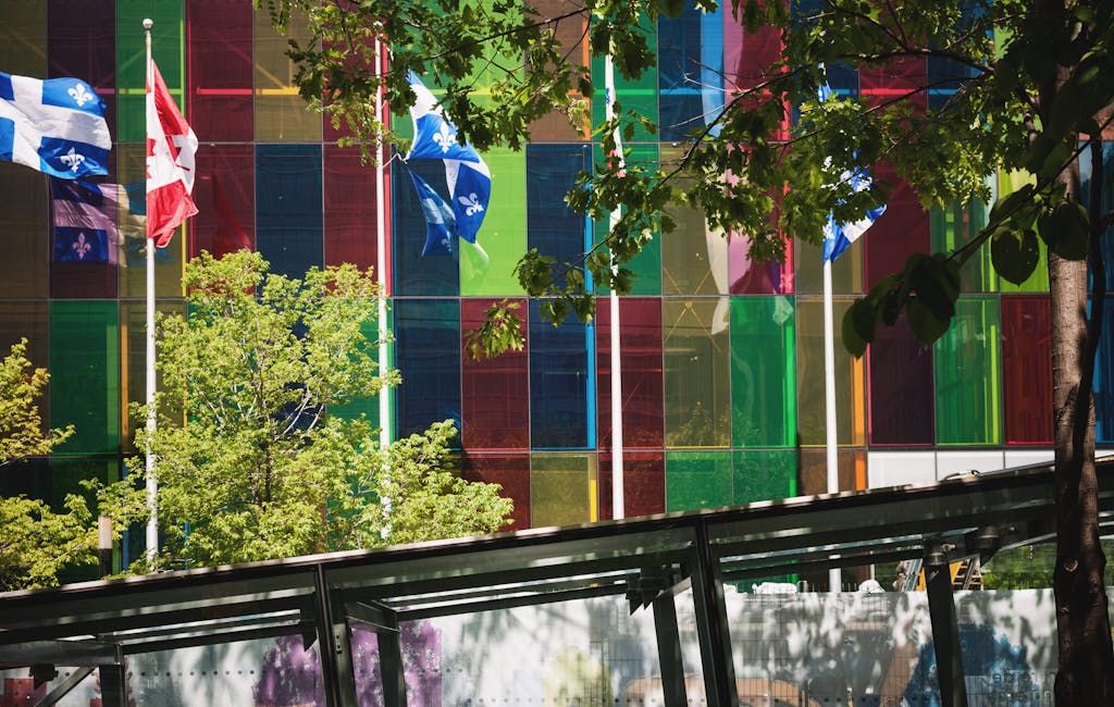 Vibrant glass building with Canadian and Quebec flags in downtown Montreal.