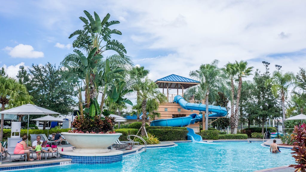 Vibrant tropical resort scene featuring a pool, waterslide, and lush palm trees, ideal for summer vacations.