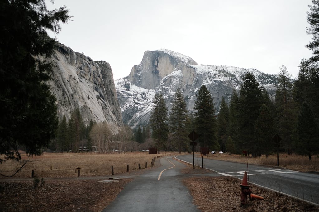 Winter landscape view of Half Dome in Yosemite National Park with snow and a winding road.